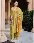 Maharani Royal Couture green and yellow mul cotton suit with digital print, dabka work, and lace finish. Model wears pearl necklace and gold heels.