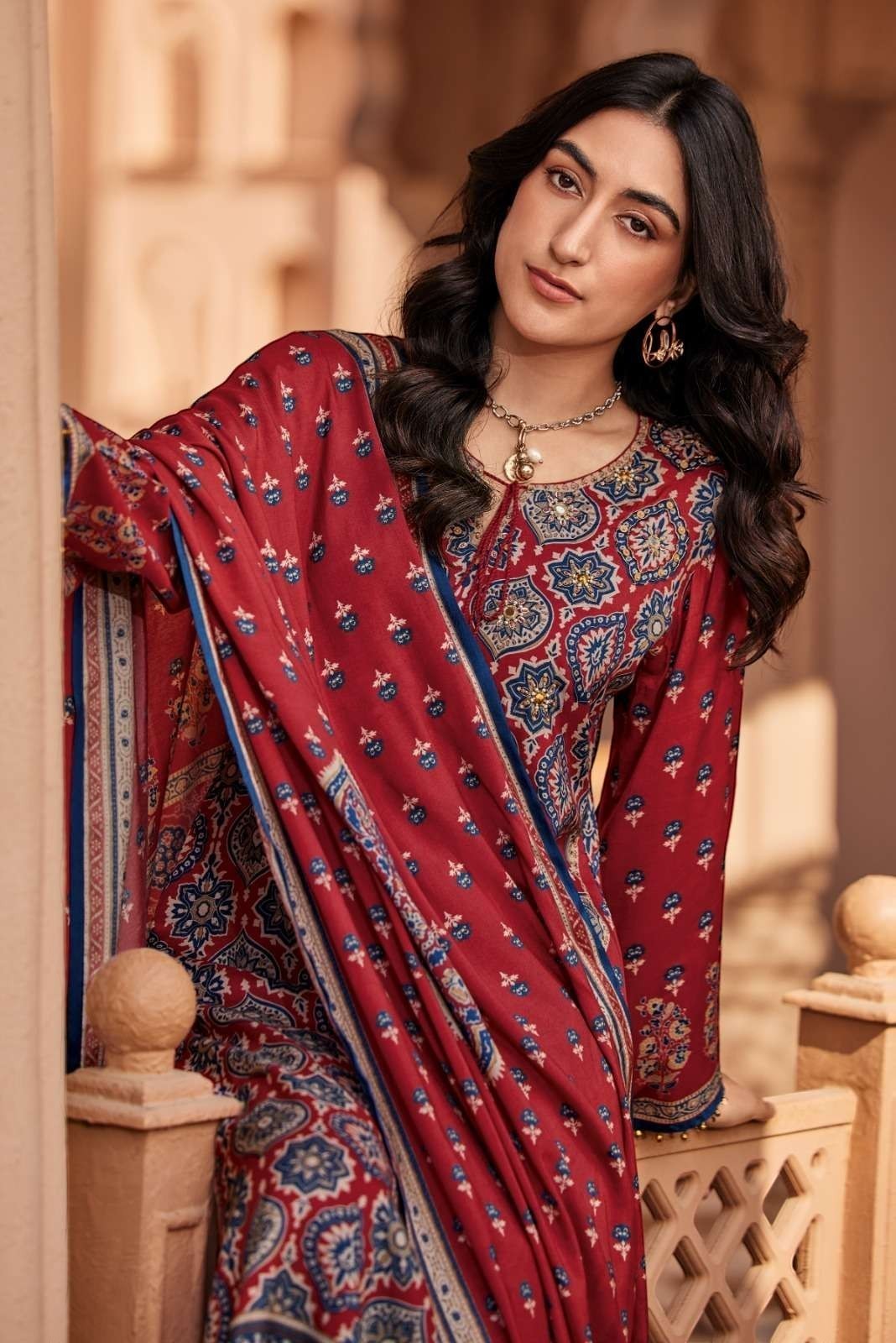 Maharani Royal Couture red viscose muslin suit with digital print and mirror handwork. Includes printed dupatta with tassels and solid bottoms.